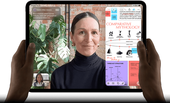 Asztrofekete iPad Pro szemből, fekvő tájolásban, lekerekített sarkokkal, fekete kijelzőkerettel. A bal és jobb szélén
      egy-egy kéz fogja, a kijelzőn élőben fordított FaceTime-beszélgetés, valamint egy oktatási célú alkalmazás jelenik meg, amely
      egy komparatív mitológiáról szóló prezentációt tartalmaz szöveggel, ábrákkal és kézzel írt jegyzetekkel